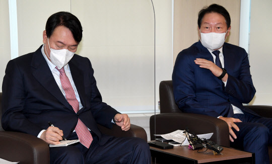 윤석열 국민의힘 대선후보가 16일 오전 서울 중구 대한상공회의소에서 최태원(오른쪽) 대한상의 회장과 간담회를 하던 중 최 회장의 발언을 수첩에 메모하고 있다. <국회사진기자단·연합뉴스>